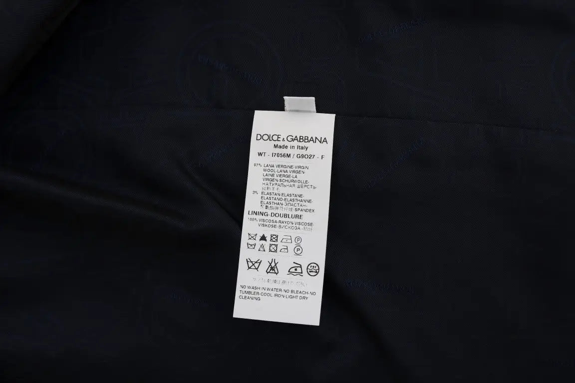 Étiquette de soin rectangulaire blanche avec texte noir attachée à un gilet dolce & gabbana bleu en laine stretch