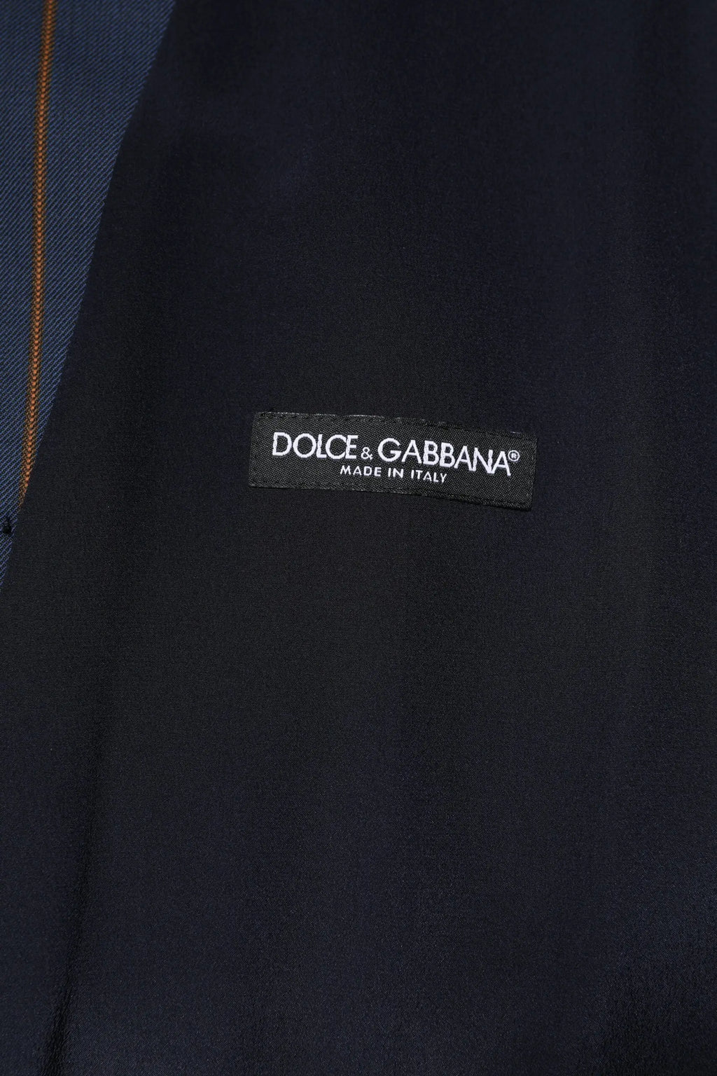 Étiquette noire dolce & gabbana avec texte blanc sur tissu bleu marine du gilet formel homme en laine à rayures bleues