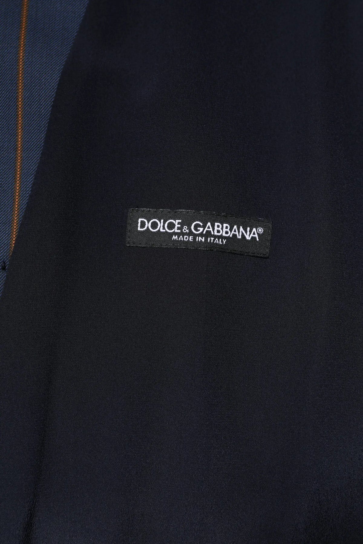 Étiquette noire dolce & gabbana avec texte blanc sur tissu bleu marine du gilet formel homme en laine à rayures bleues