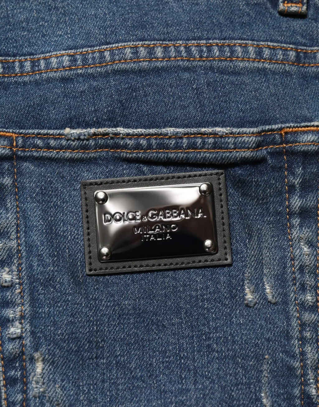 Patch en cuir noir avec plaque métallique dolce & gabbana milano italia cousue sur denim bleu déchiré arrière des jeans skinny pour hommes