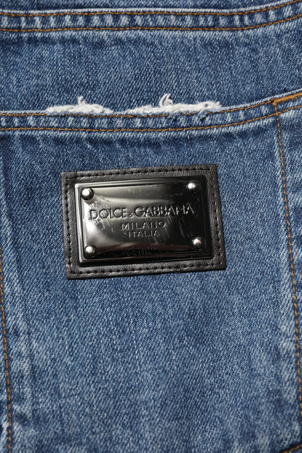 Plaque en métal avec cuir noir dolce gabbana milano italia fixée sur un jean en denim bleu délavé