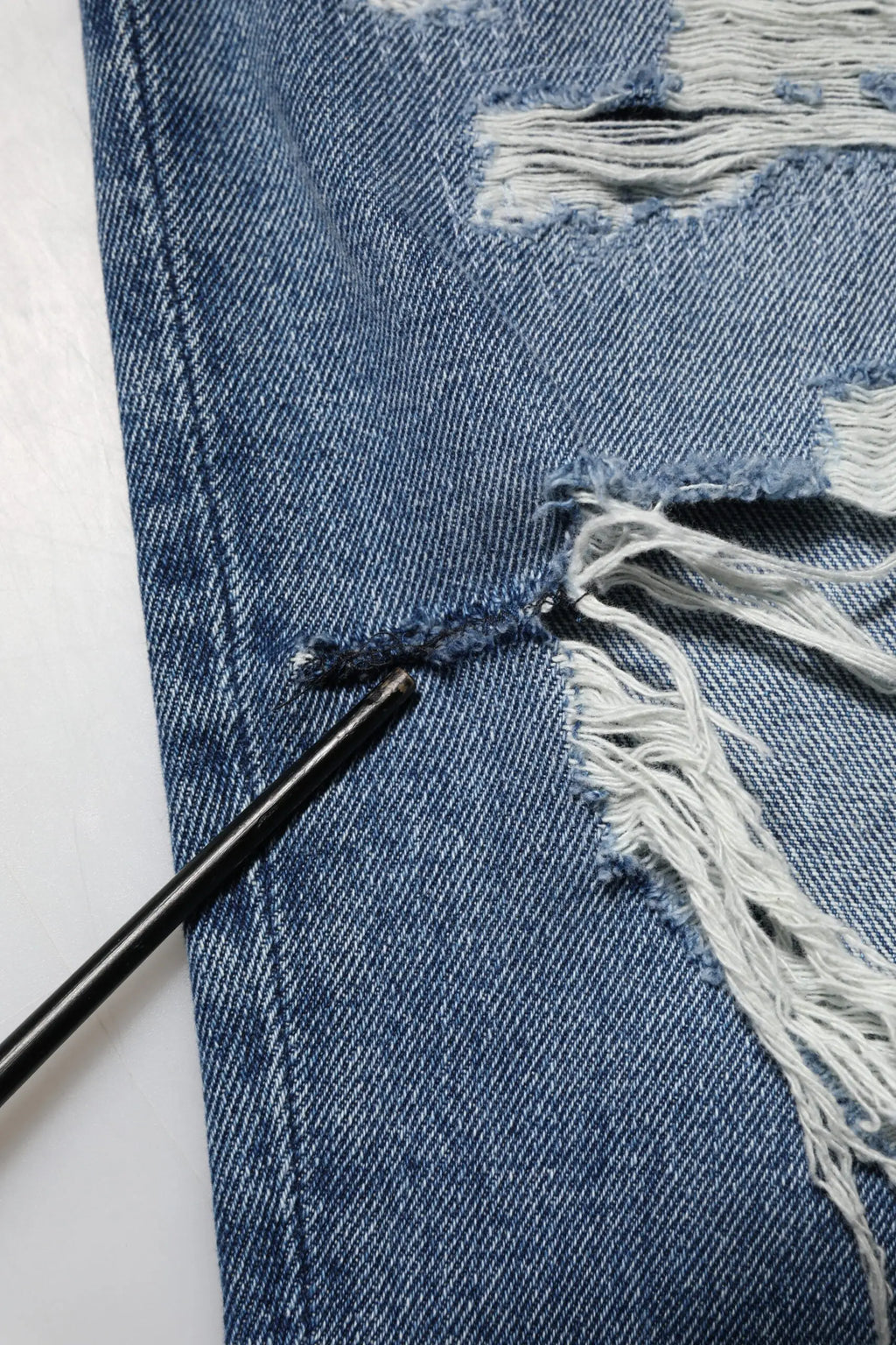 Un crochet noir en crochet repose contre un jean bleu déchiré et usé dolce & gabbana taille haute pour femme