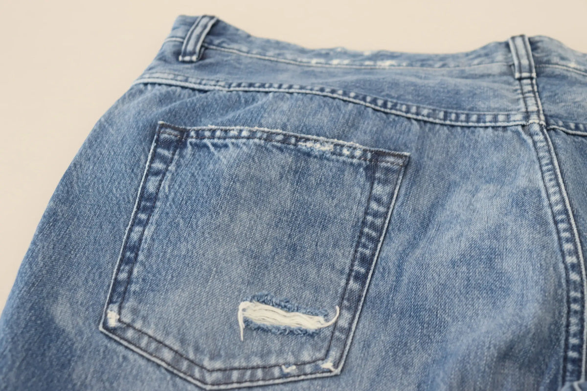 Détail de la poche arrière des jeans denim délavé bleu dolce & gabbana en coton avec couture blanche contrastée et bord effiloché