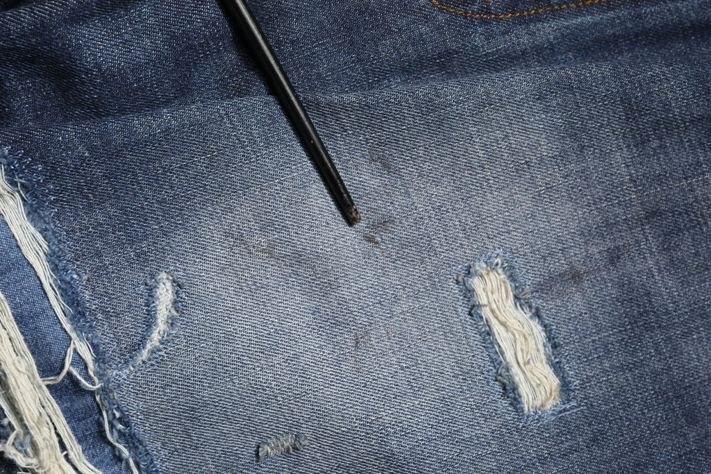 Détresse denim bleu lavé coton homme jean dolce & gabbana avec bords effilochés et petite tache sombre en haut à gauche