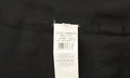 Étiquette blanche rectangulaire dolce & gabbana made in italy cousue sur tissu foncé dun gilet en coton marron