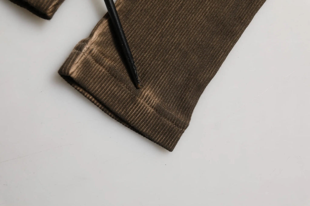 Le poignet d’un pull henley dolce & gabbana marron en coton côtelé avec un léger éclat