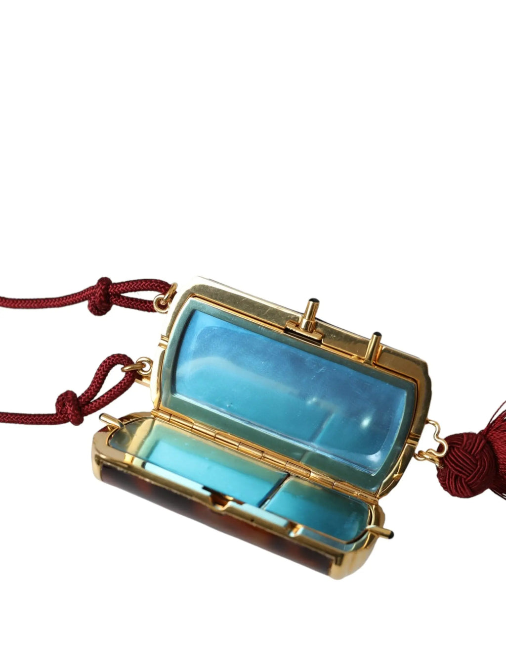 Compact rectangulaire doré avec intérieur translucide bleu et cordons à pompons rouges dans sac à maquillage dolce & gabbana léopard marron