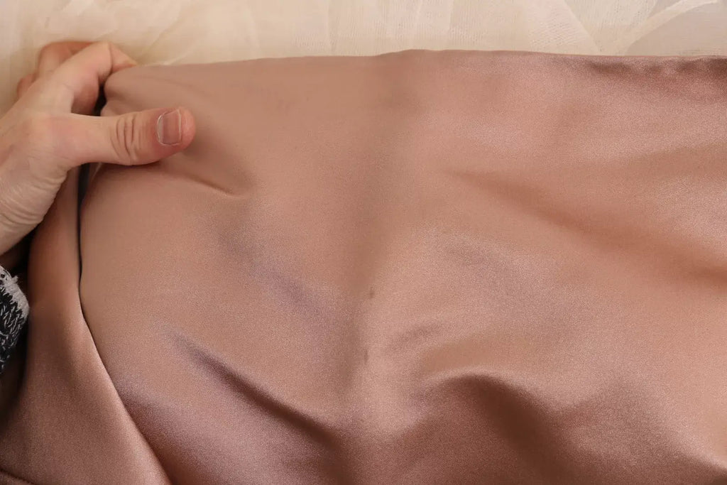 Une taie d’oreiller en soie rose poudré douce et légèrement brillante associée à une robe boule cristal dolce & gabbana