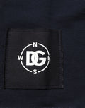 Étiquette noire tissée avec logo dg brodé blanc entouré de points de compas sur sweat en coton bleu foncé dolce & gabbana