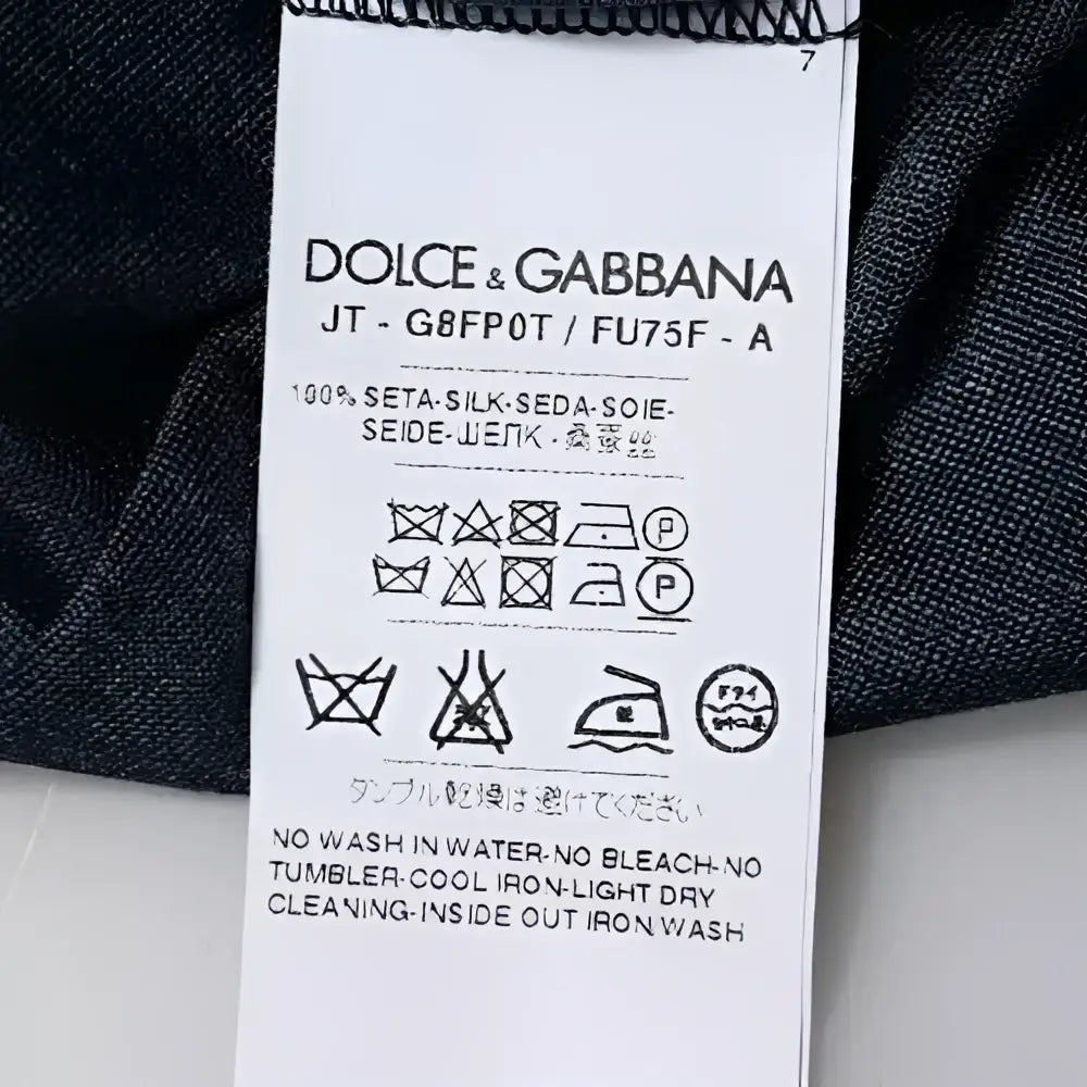 Étiquette de soin en tissu blanc au dos d un t shirt dolce & gabbana bleu foncé en soie 100 pour cent
