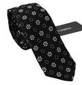 Cravate classique dolce & gabbana en soie noire avec motif floral blanc délicat et étiquette de marque visible