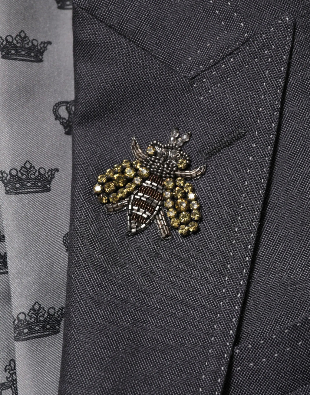 Une broche abeille détaillée perles avec accents or et noir orne un blazer en laine gris foncé dolce & gabbana