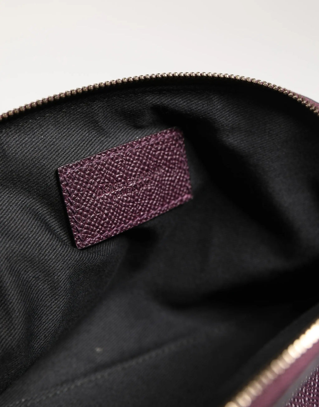 Étiquette de marque en cuir violet foncé texturé avec lettrage embossé dans l’intérieur noir du portefeuille dolce & gabbana