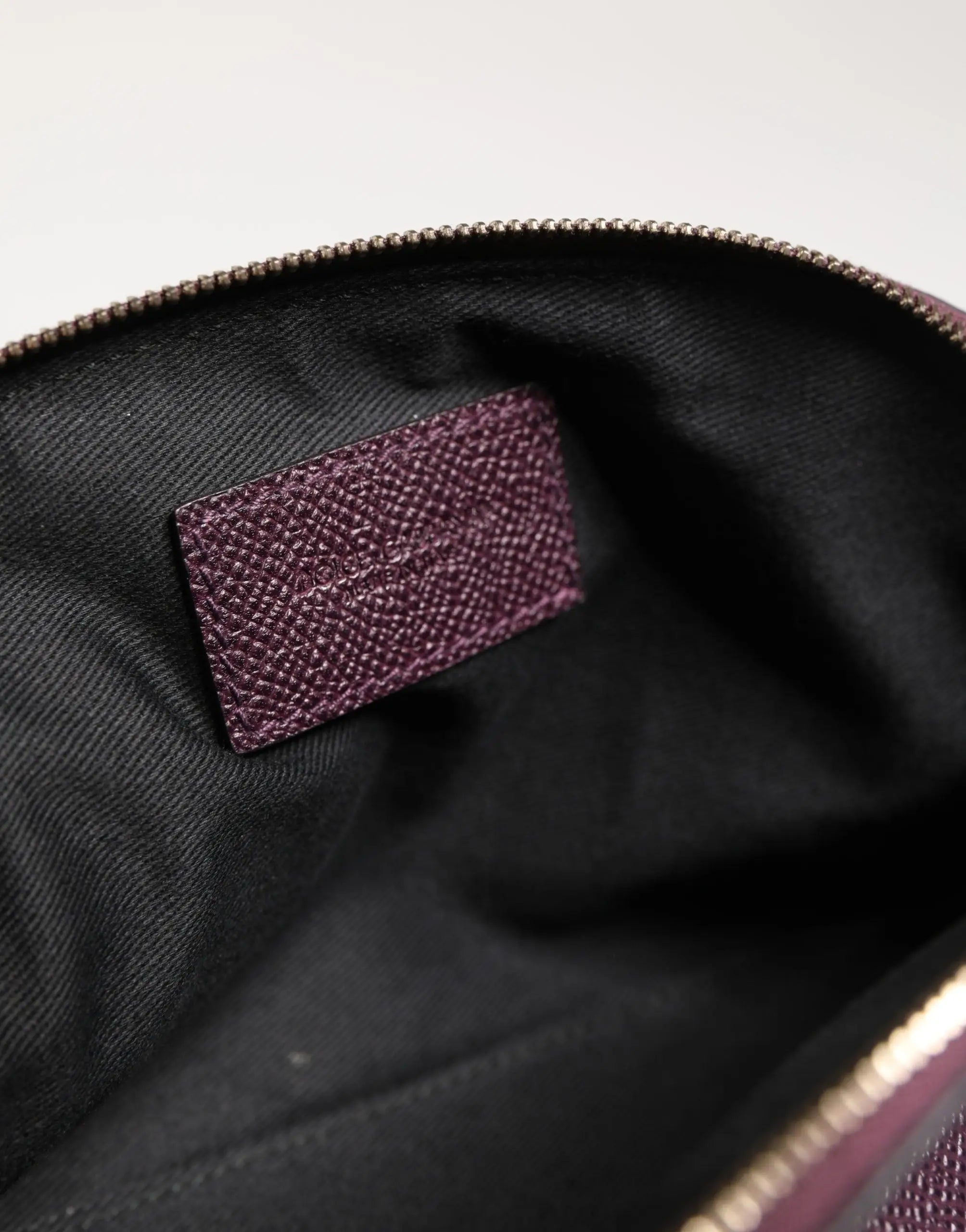 Étiquette de marque en cuir violet foncé texturé avec lettrage embossé dans l’intérieur noir du portefeuille dolce & gabbana