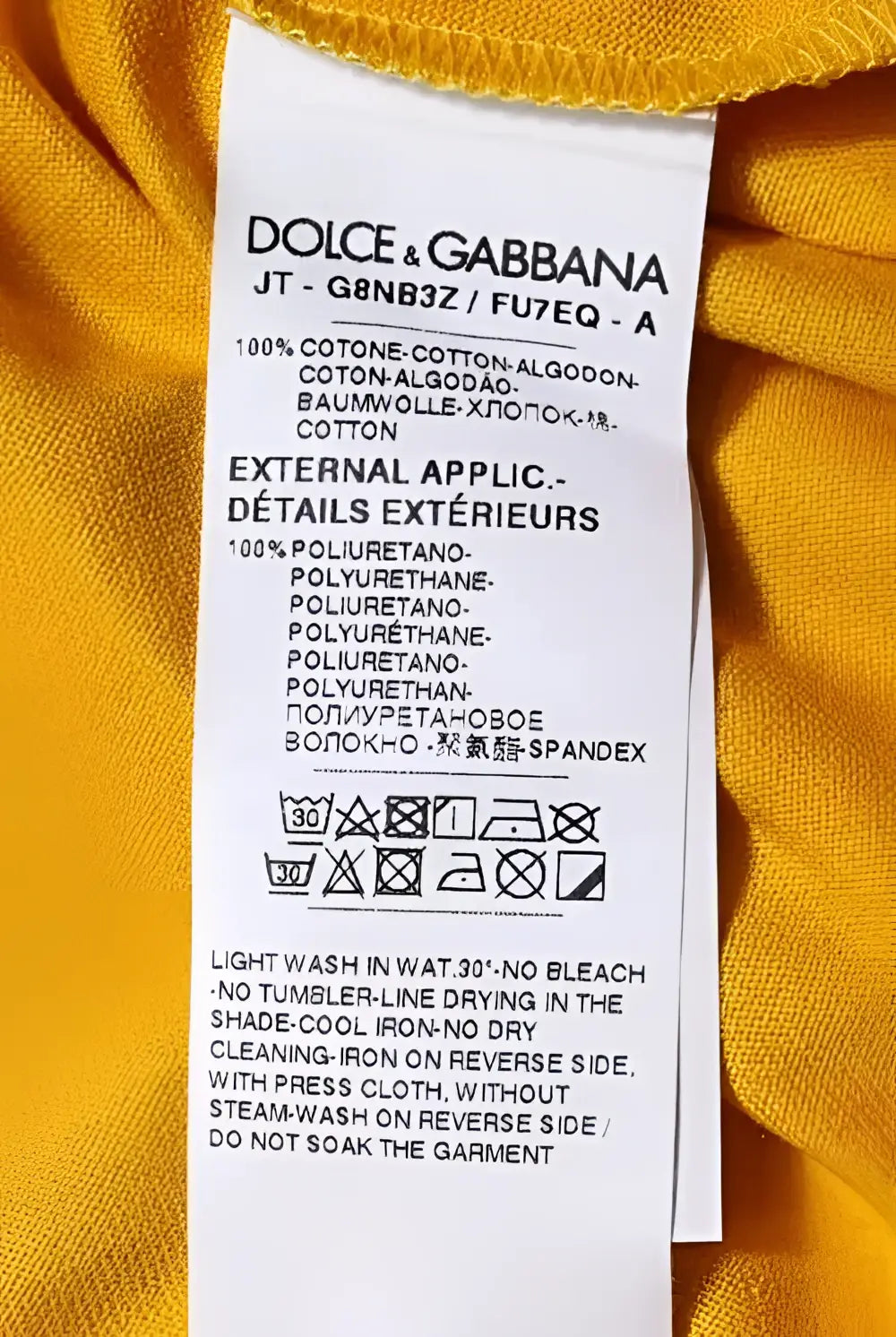 Étiquette de soin jaune dolce and gabbana avec texte noir indiquant la composition du tissu d un t shirt jaune foncé à logo manches courtes col rond