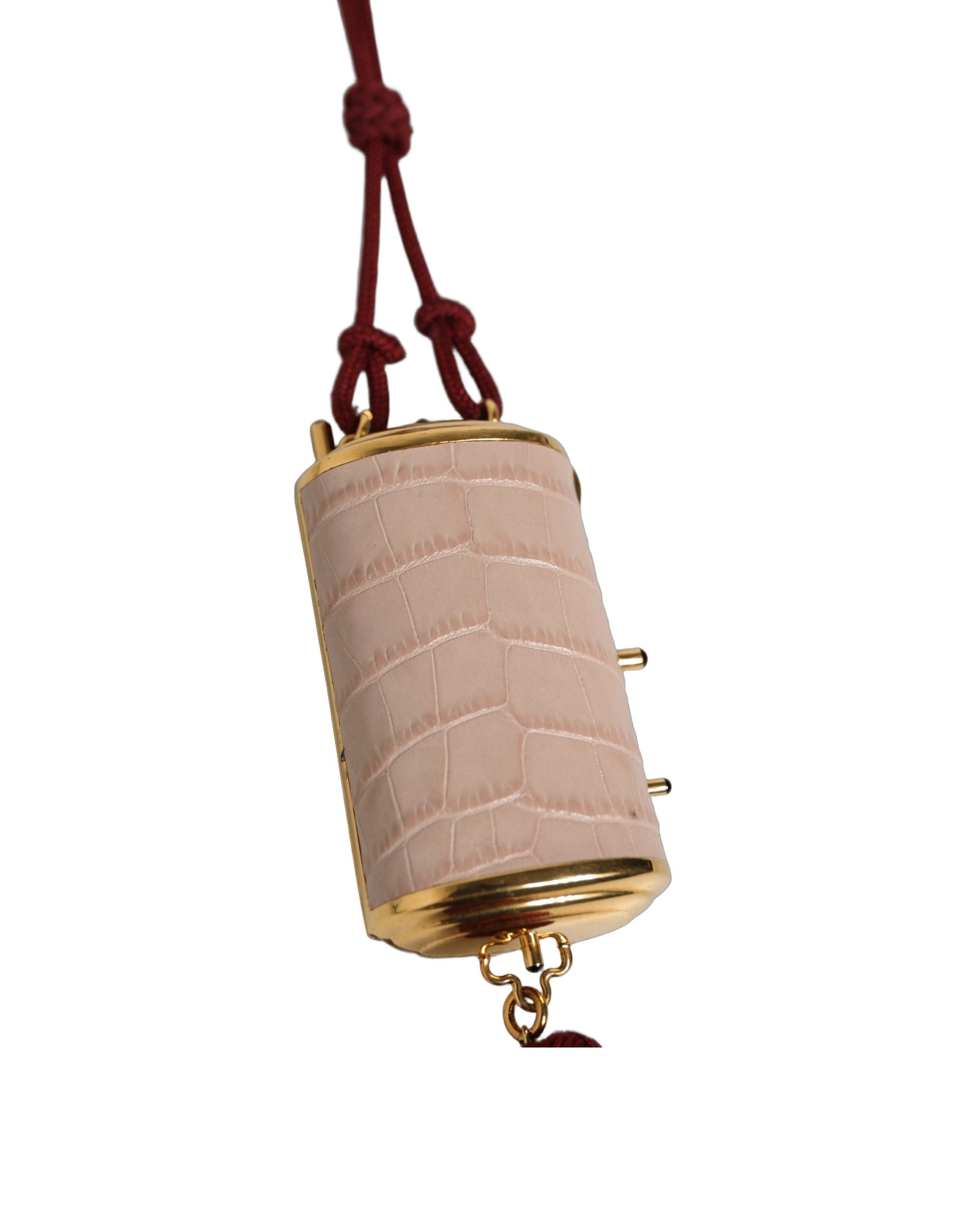 Trousse à maquillage en cuir exotique rose Dolce & Gabbana avec mini miroir et pompons en tassel, élégante et sophistiquée.