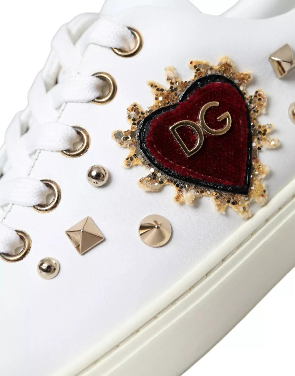 Chaussures sneakers en cuir blanc Dolce & Gabbana avec cœur rouge doré, visible en détail sur la photo.