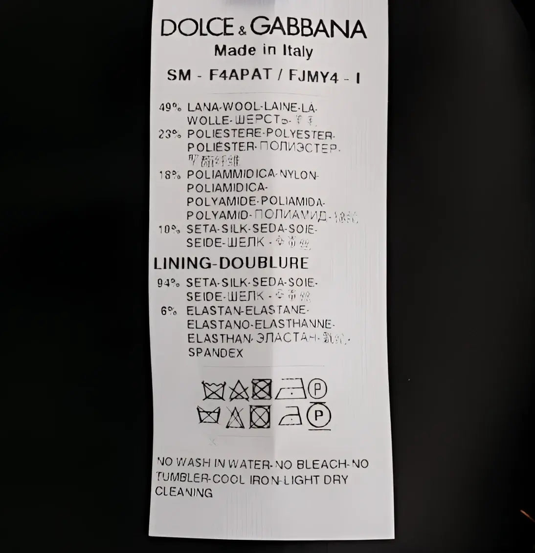 Étiquette d’entretien blanche dolce & gabbana avec texte noir indiquant la composition et lavage de jupe mini dorée noire