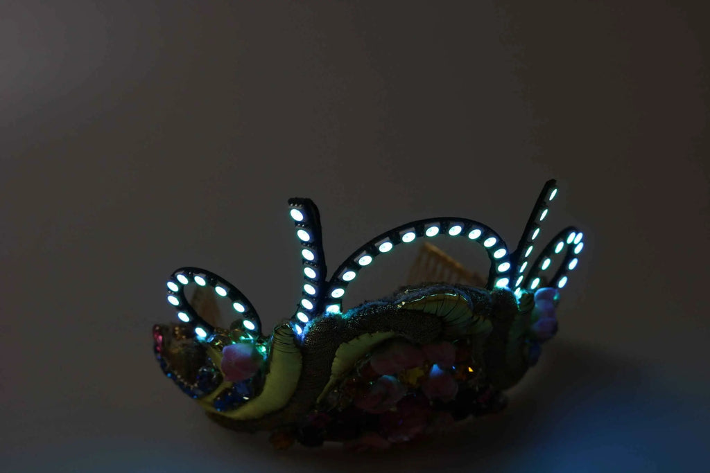 Une tiare led ornate dolce & gabbana en laiton doré avec base foncée ornée de sequins irisés et cristaux étincelants
