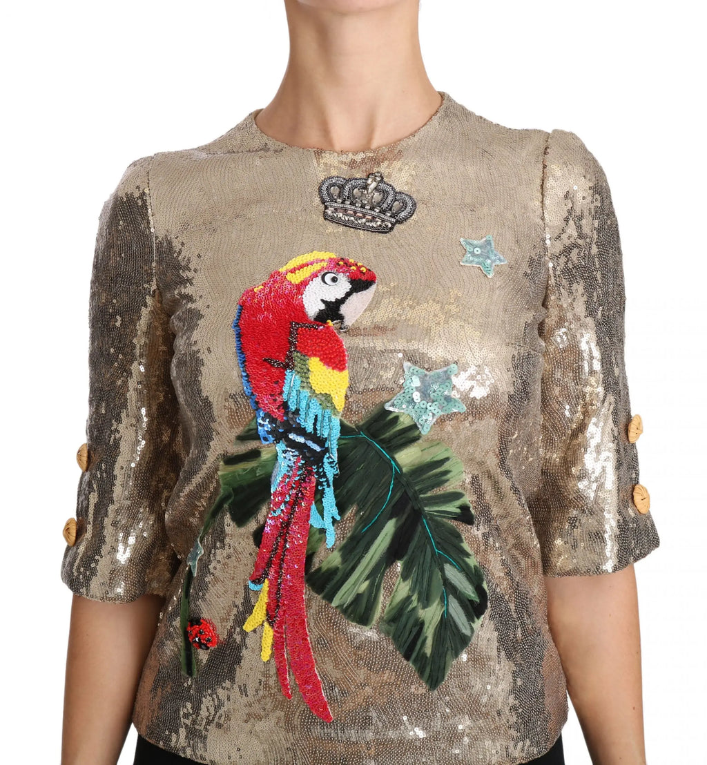 Blouse dolce & gabbana en sequins or avec applique perroquet colorée en plumes rouge jaune et bleu sur feuilles vertes
