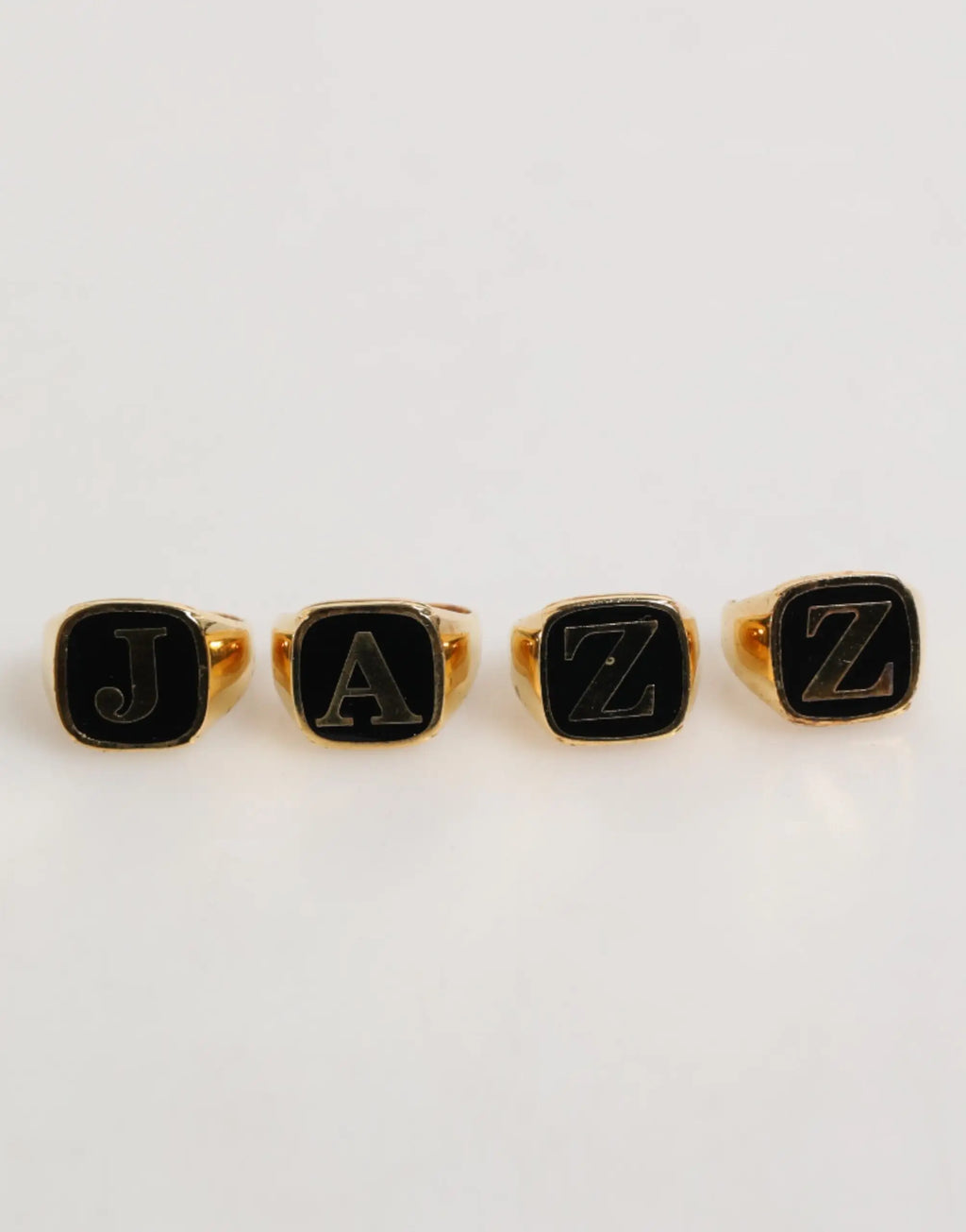 Quatre bagues ajustables dolce & gabbana en laiton doré avec lettres jazz en émail noir et argent sur le dessus