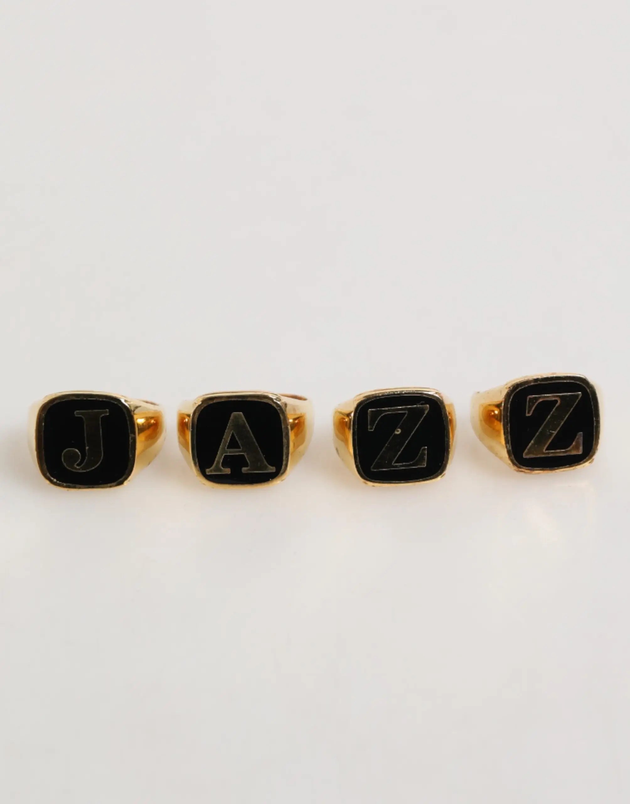 Quatre bagues ajustables dolce & gabbana en laiton doré avec lettres jazz en émail noir et argent sur le dessus
