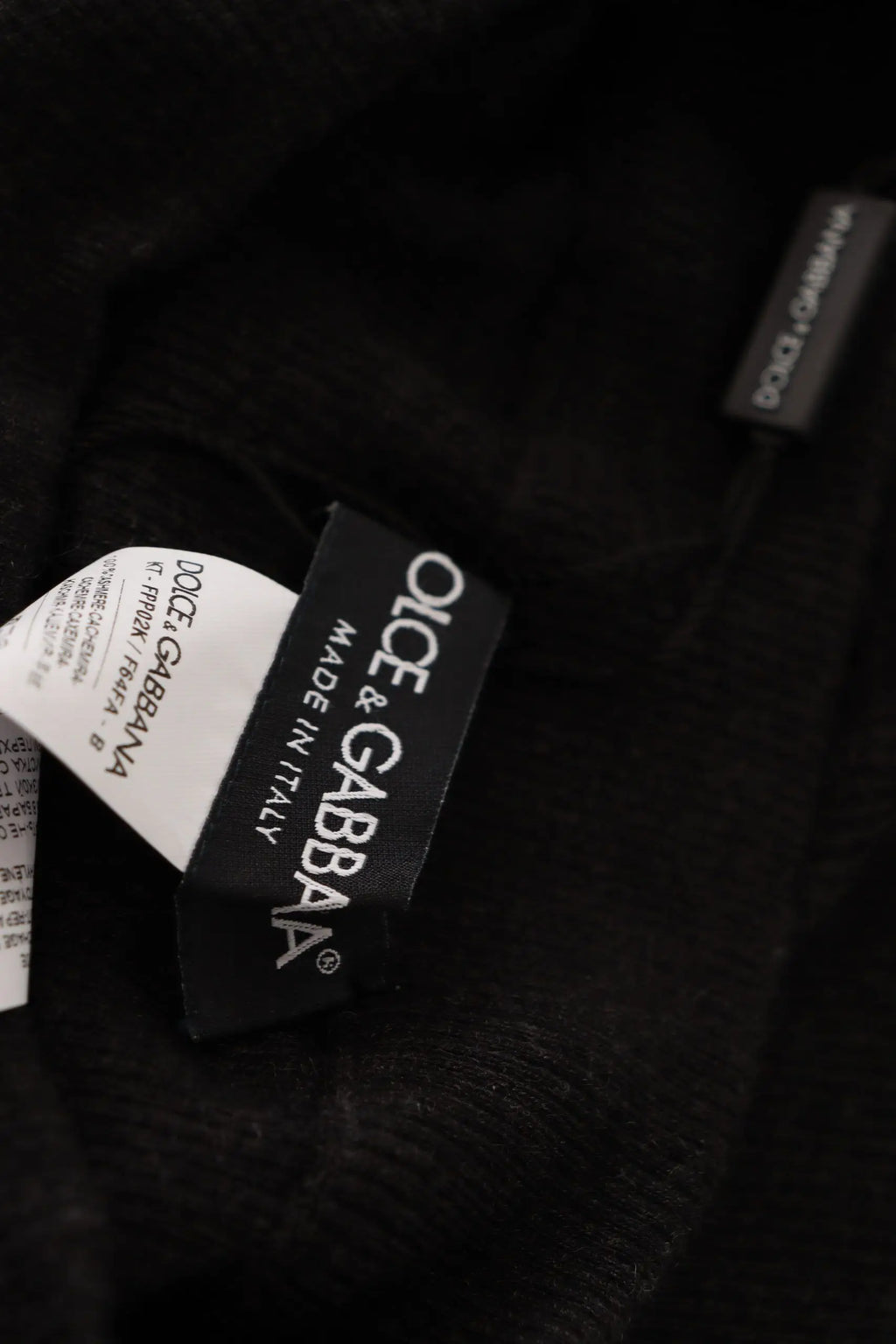Étiquette noire dolce gabbana avec lettrage blanc sur des collants gris en cachemire dolce gabbana