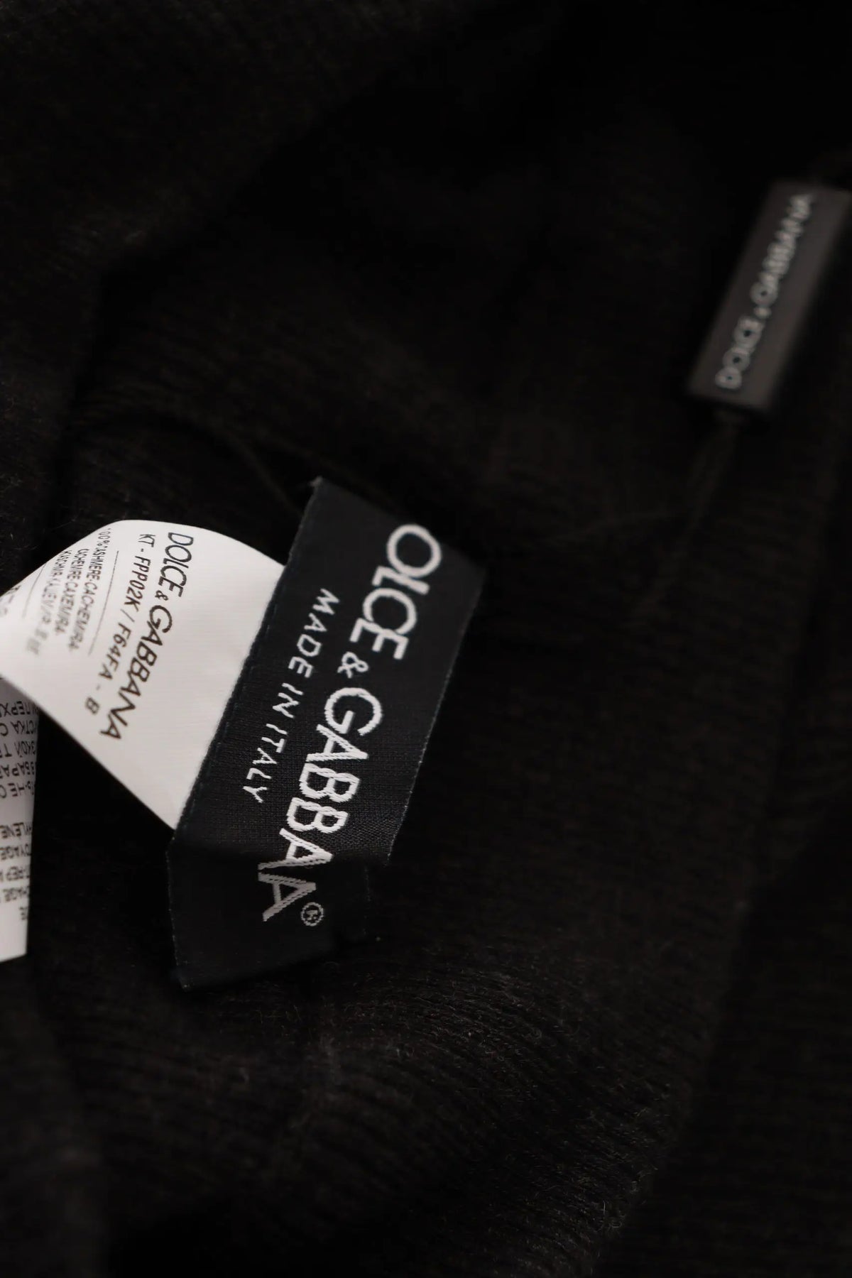 Étiquette noire dolce gabbana avec lettrage blanc sur des collants gris en cachemire dolce gabbana