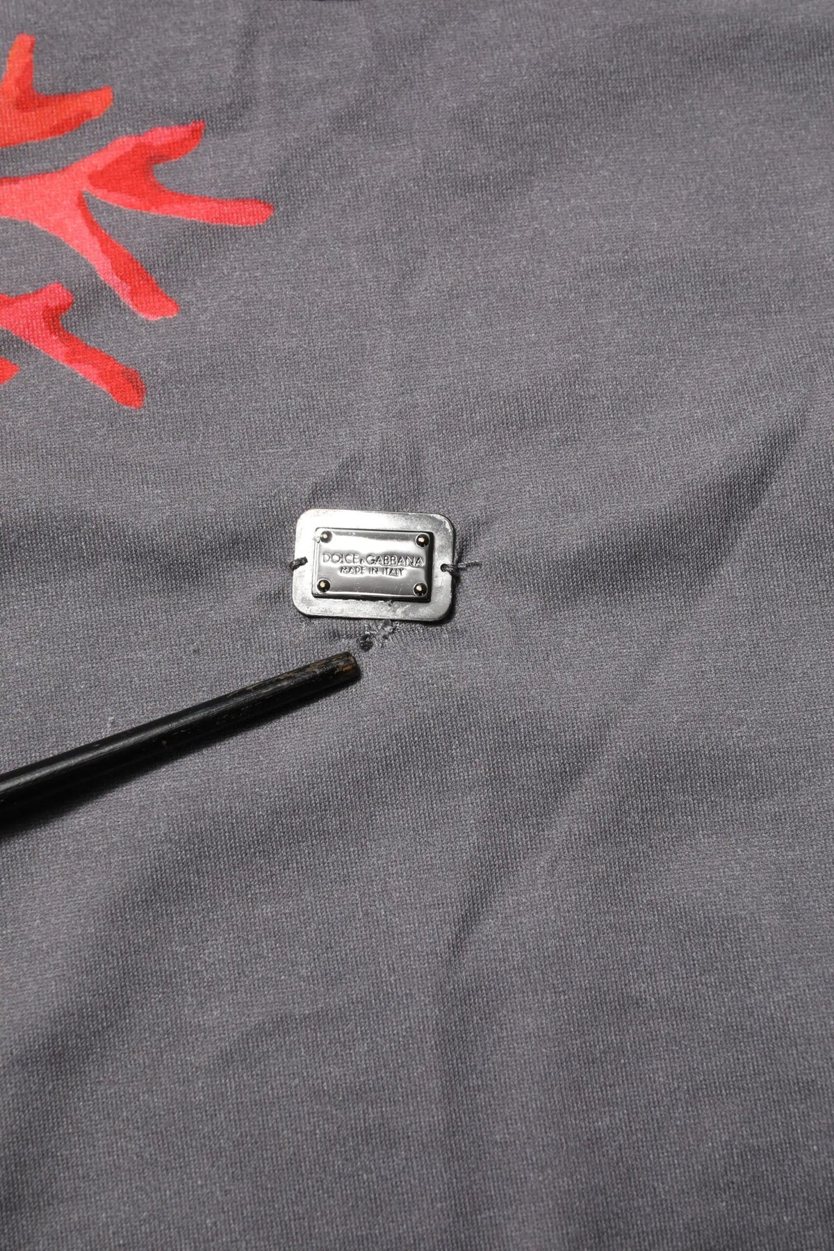 Plaque rectangulaire en métal argenté dolce & gabbana fixée sur tissu gris du t-shirt coton avec logo corail