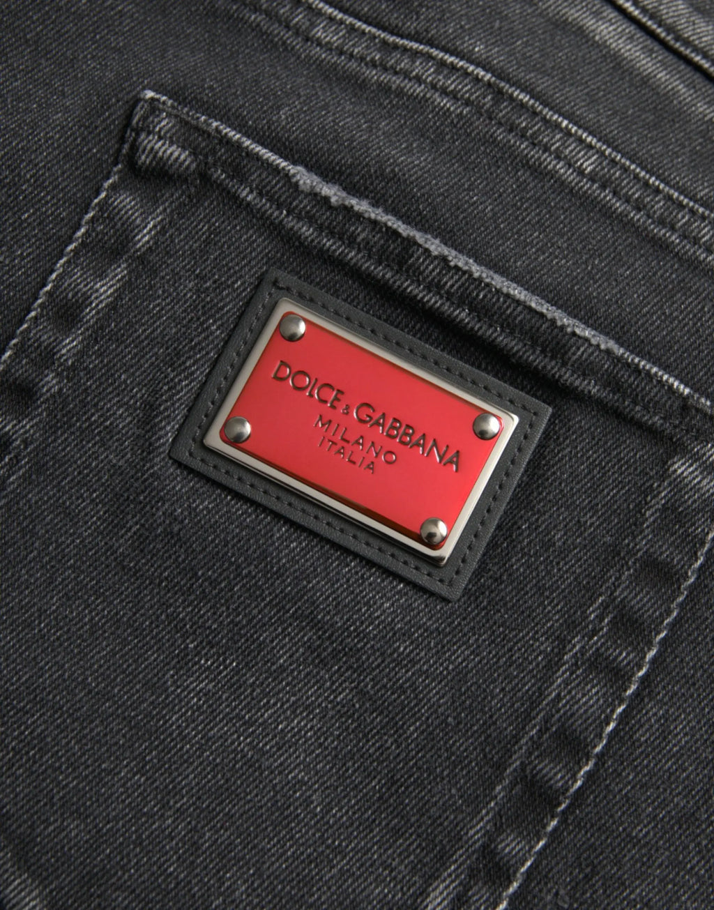 Étiquette rouge rectangulaire avec lettrage argenté et rivets métalliques cousue sur jean skinny gris en coton stretch dolce gabbana