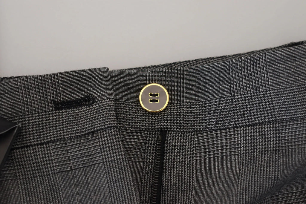 Un bouton doré classique à deux trous centré sur la taille d’un pantalon en laine gris à carreaux dolce & gabbana