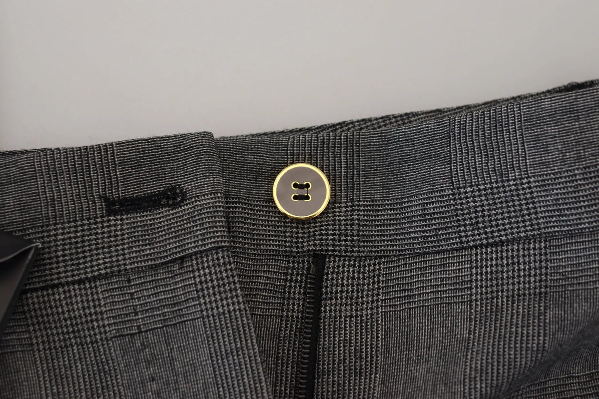 Un bouton doré classique à deux trous centré sur la taille d’un pantalon en laine gris à carreaux dolce & gabbana