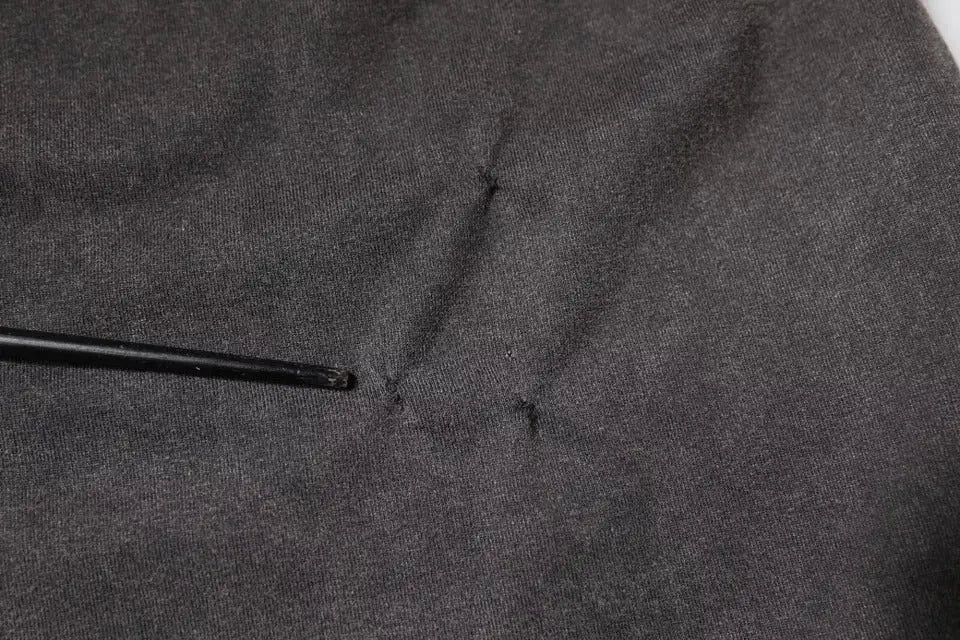 Un crochet noir repose sur un tissu gris foncé texturé à côté d un t shirt dolce gabbana gris imprimé léopard en coton