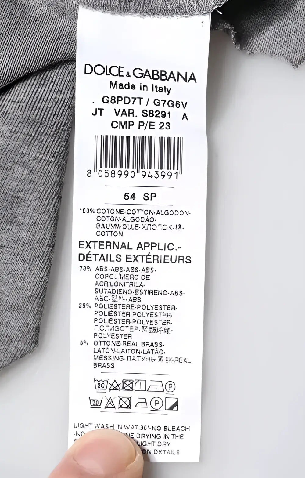 Étiquette de soin blanche dolce and gabbana avec texte noir et composition coton polyester laiton sur t shirt gris logo col rond manches courtes