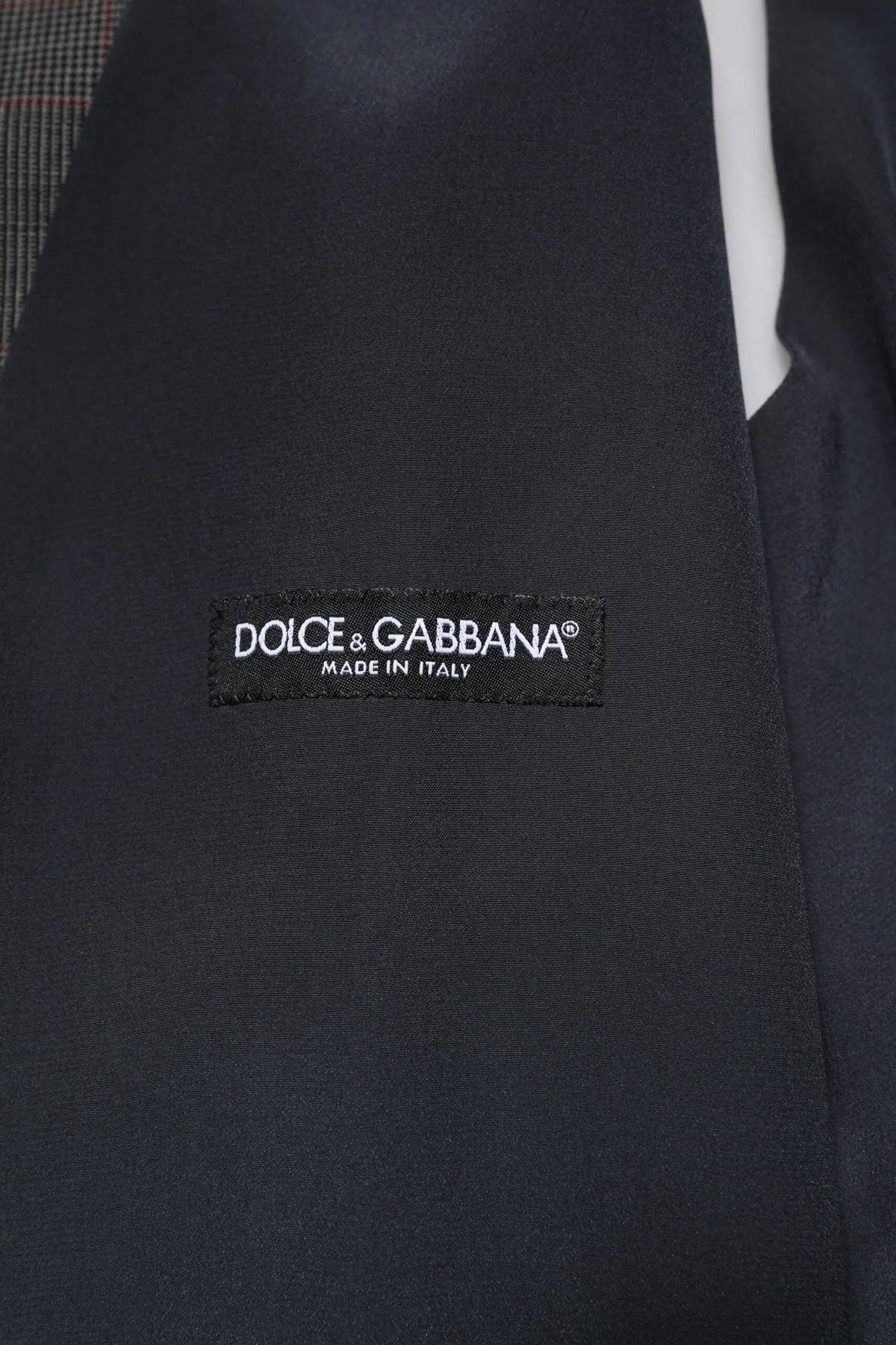 Étiquette noire dolce & gabbana avec texte blanc brodé sur un gilet formal en laine grise à carreaux made in italy