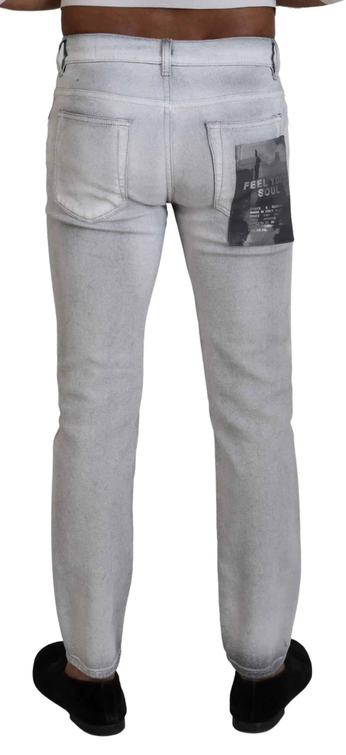 Vue de dos d un jean skinny homme dolce gabbana en denim gris clair délavé avec un patch noir sur la poche arrière droite