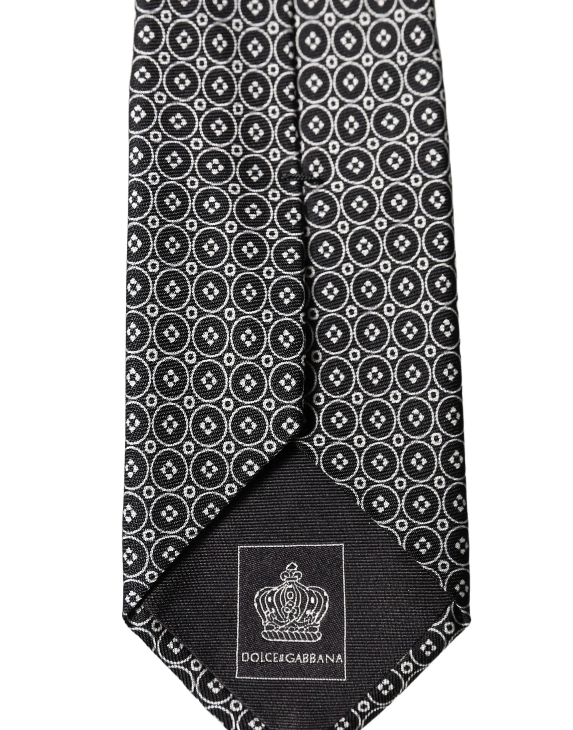 Cravate homme dolce gabbana en soie noire avec motif géométrique blanc et étiquette de marque au bout