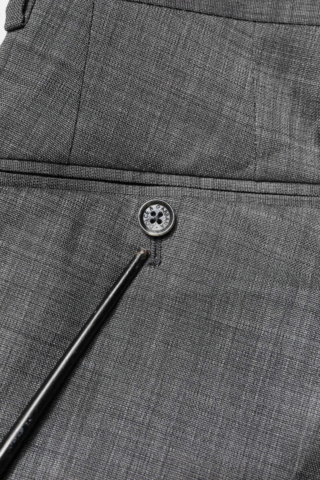 Boutonnière en tissu gris foncé texturé avec bouton métallique à quatre trous sur costume gris en laine dolce & gabbana