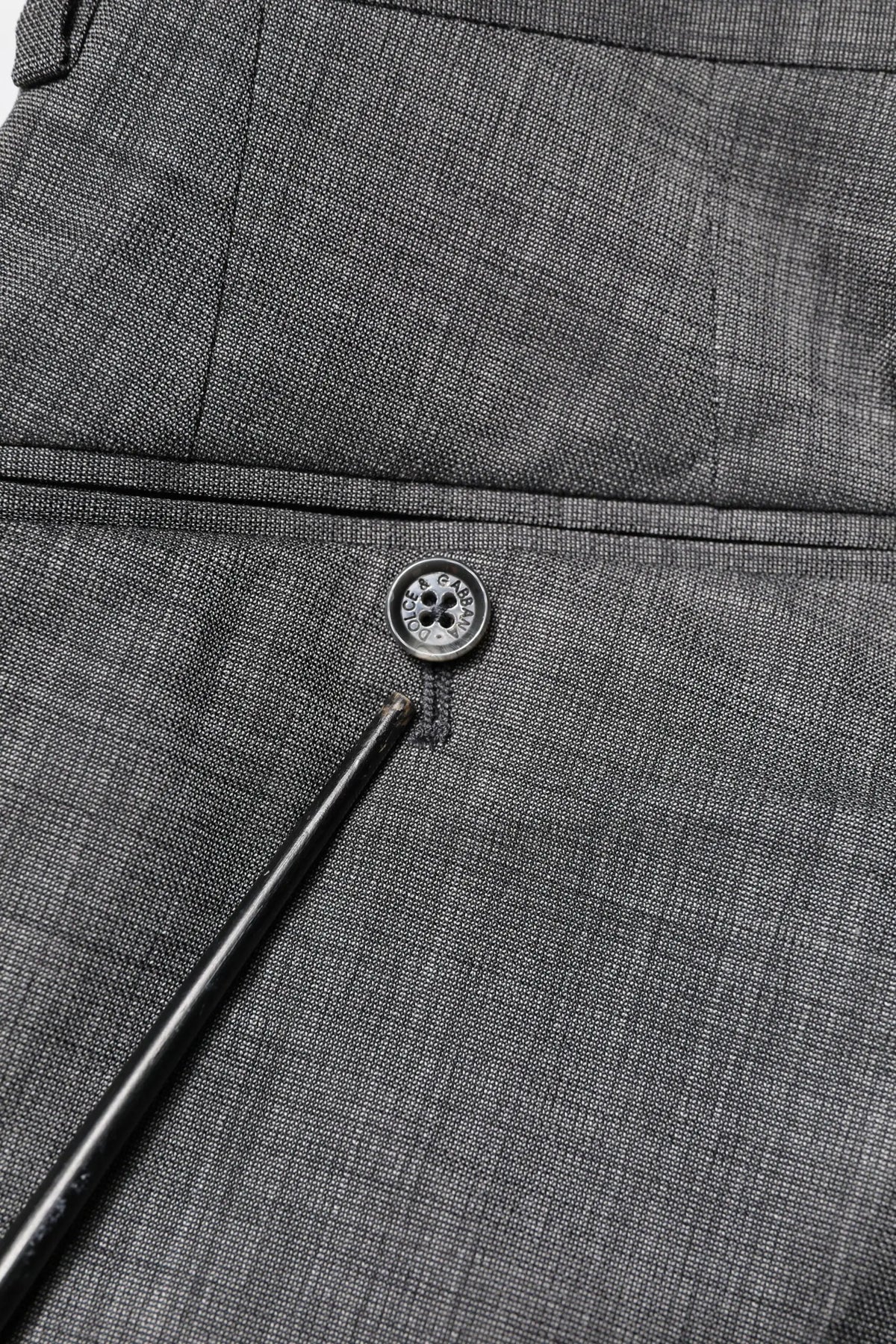 Boutonnière en tissu gris foncé texturé avec bouton métallique à quatre trous sur costume gris en laine dolce & gabbana