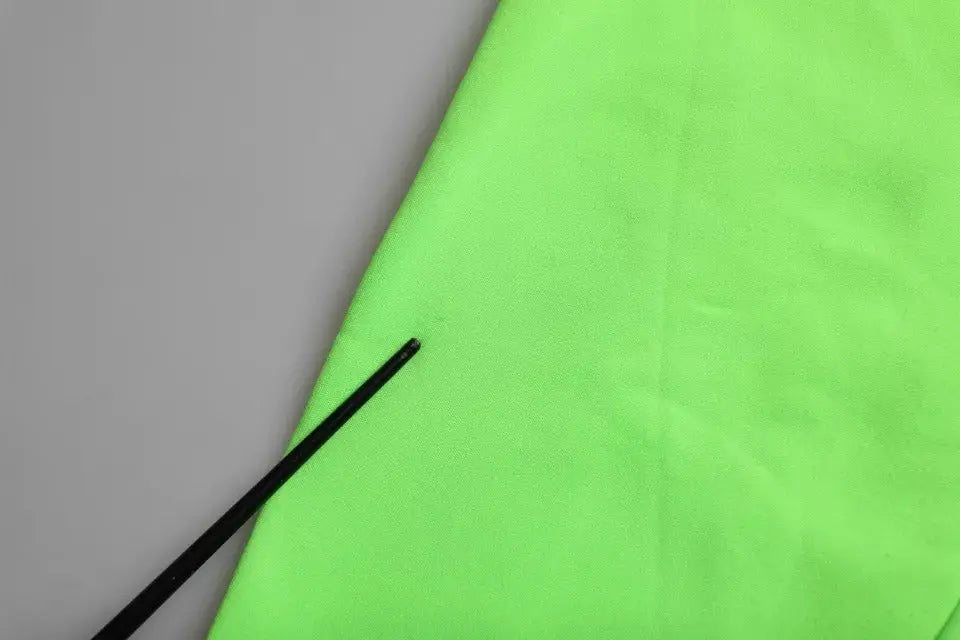 Pull-over dolce & gabbana vert avec cœur patchwork en tissu néon vert et baguette noire diagonale sur surface texturée