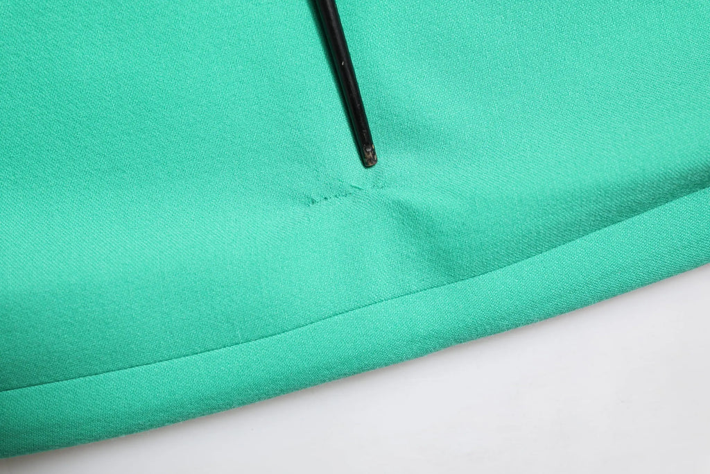 Gros plan sur une robe mini verte dolce & gabbana en tissu teal avec fermeture éclair noire et couture soignée