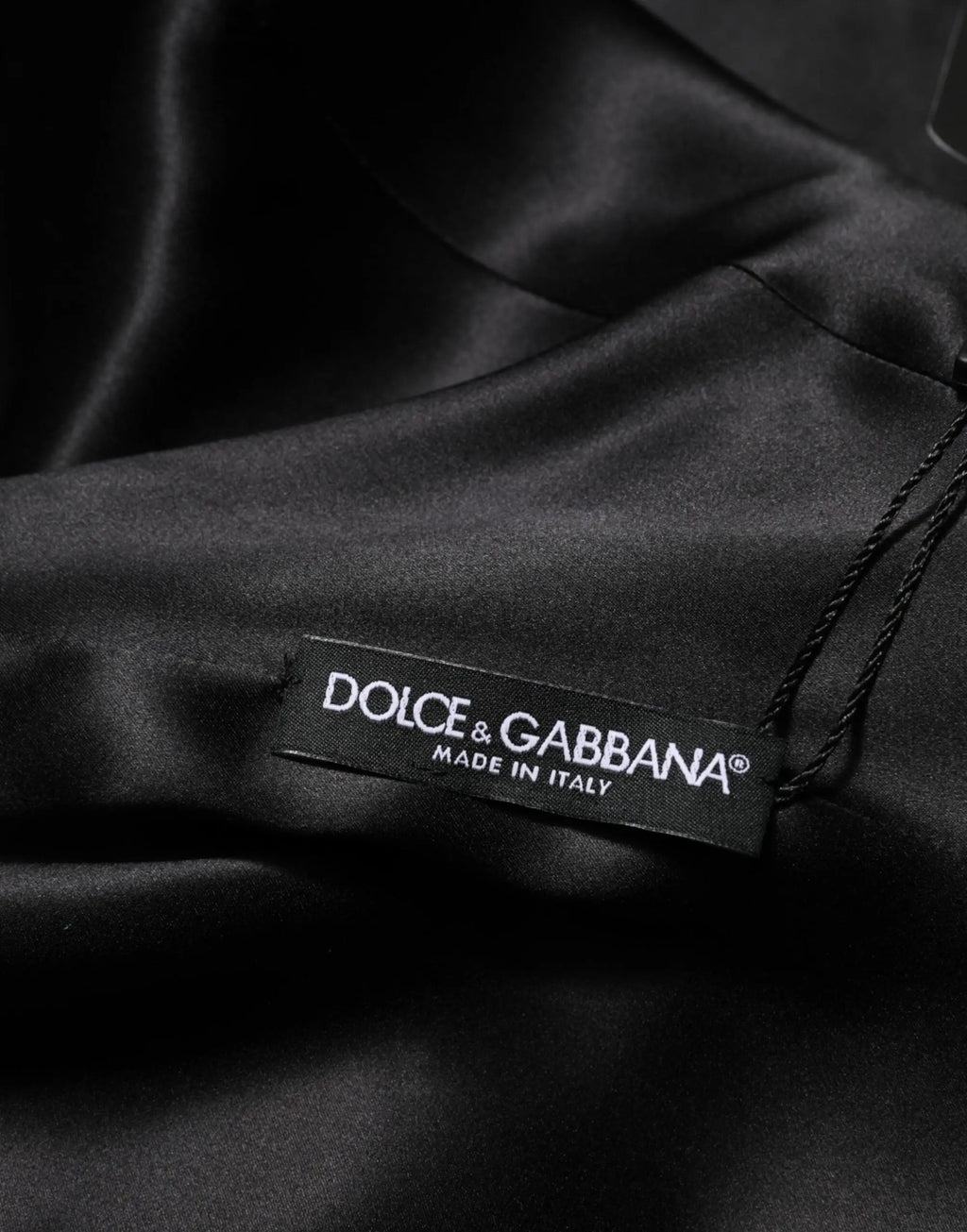 Tissu satiné noir avec étiquette dolce & gabbana indiquant une robe mini manches longues verte en viscose et acétate italienne