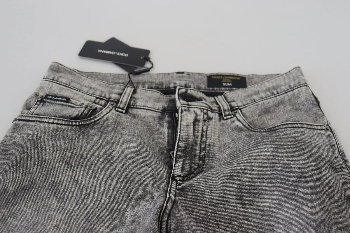 Un jean slim fit gris délavé en coton avec des effets usés et une étiquette dolce & gabbana sur la ceinture