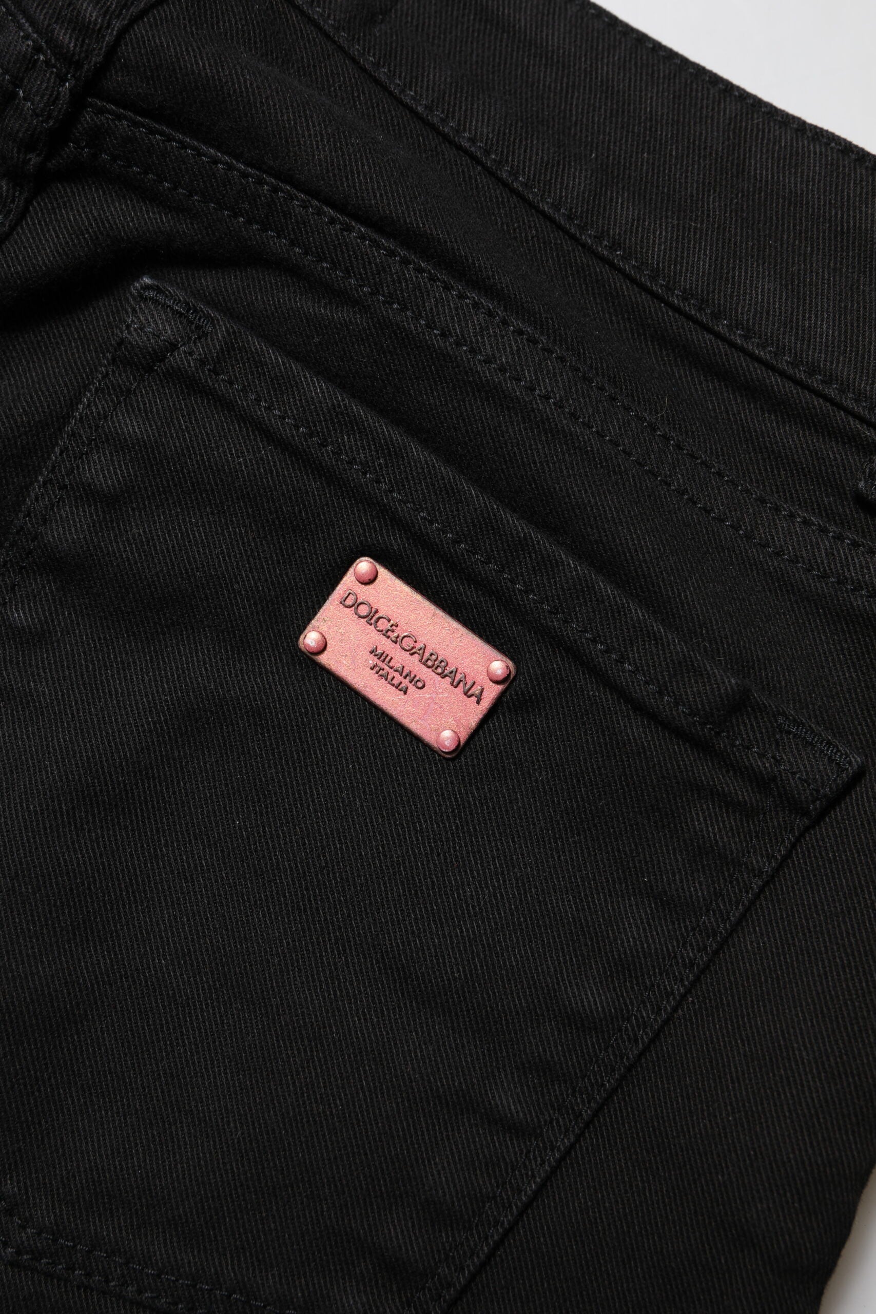 Jeans skinny en coton noir Dolce & Gabbana avec taille mi-haute, visibles sur fond neutre.