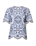 Haut Dolce & Gabbana en dentelle bleue avec col rond et œillets, manches courtes et coupe élégante.