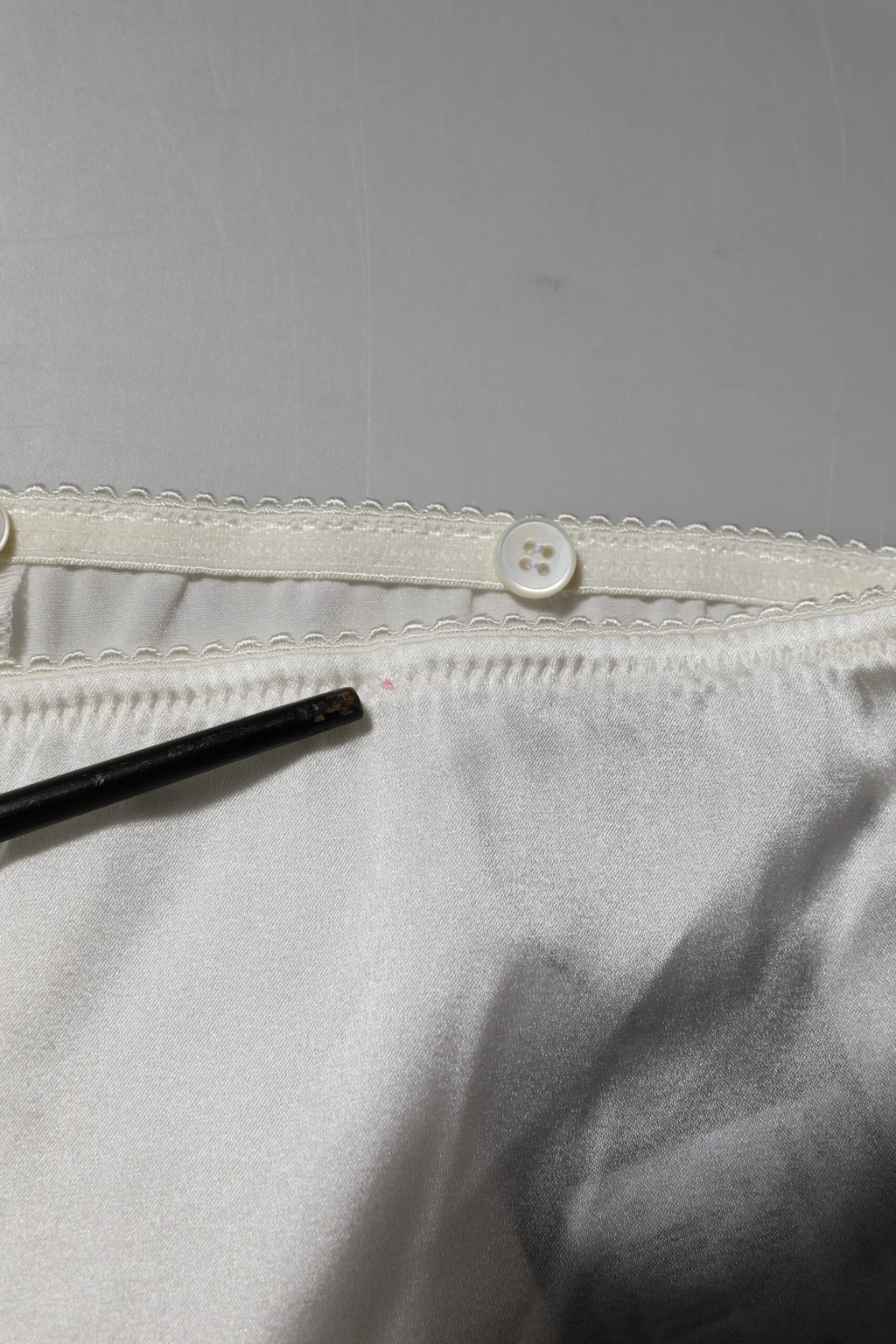 Pantalons en soie ivoire Dolce & Gabbana, coupe tapered et taille haute, visibles en détail sur l'image.