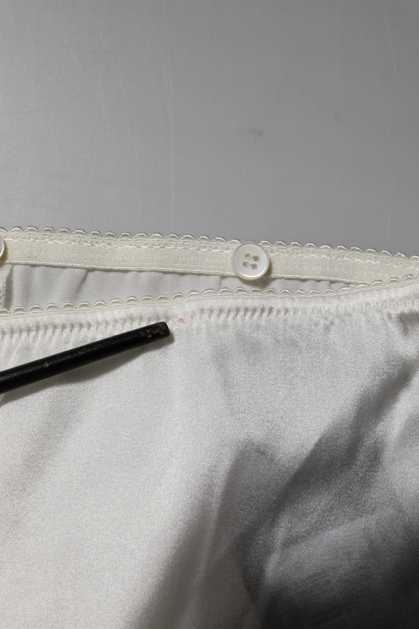 Pantalons en soie ivoire Dolce & Gabbana, coupe tapered et taille haute, visibles en détail sur l'image.