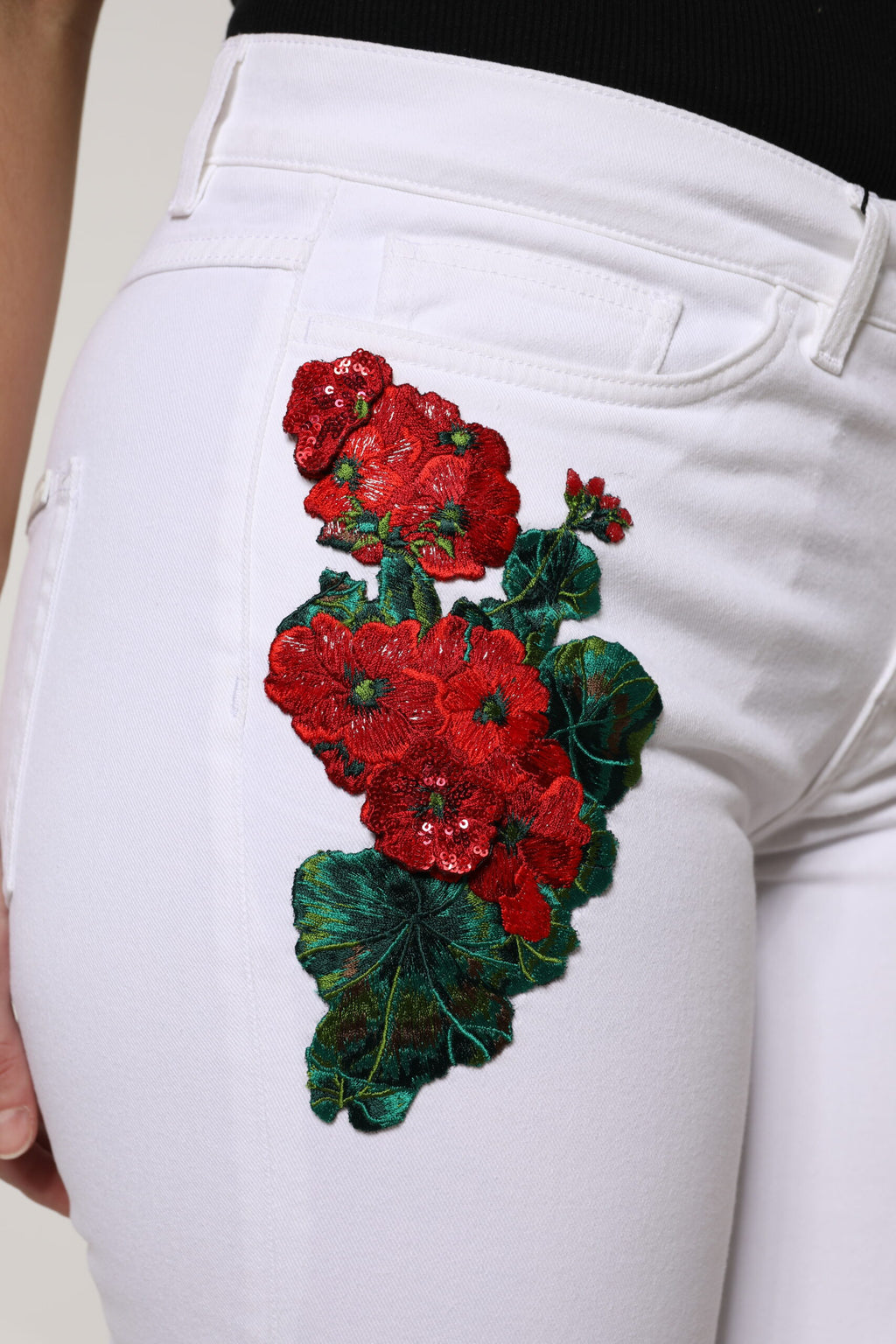Jeans en denim blanc Dolce & Gabbana à sequins floraux, style girly avec détails élégants et motifs floraux.