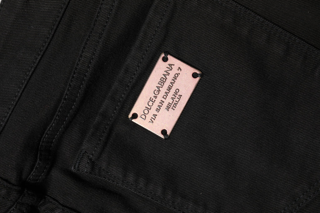 Jeans slim en coton noir Dolce & Gabbana, taille mi-haute, coupe ajustée et élégante, visibles sur la photo.
