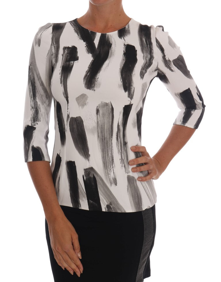 Blouse blanche et noire à rayures imprimées de Dolce & Gabbana, haut élégant en tissu léger avec col et manches longues.